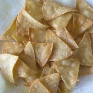 fried tortilla chips draining on paper towels