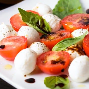 Caprese: cherry tomato, mozzarella balls and basil leaves with balsamic vinegar