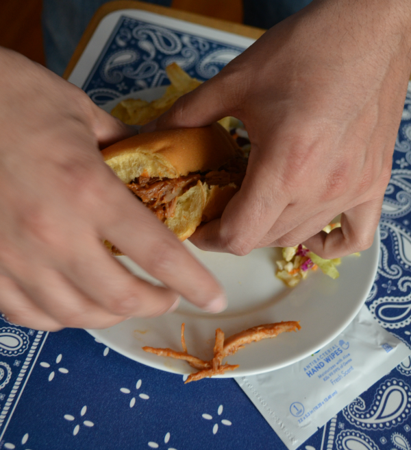 man's hands holding slow cooker bbq pork sandwich