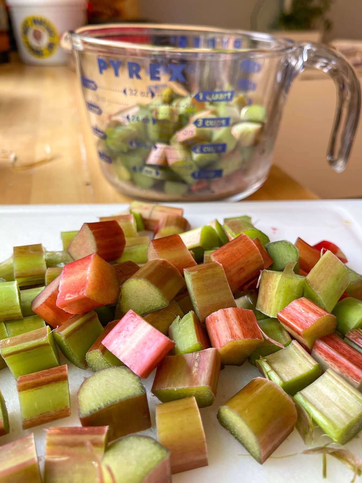 Chopped rhubarb on cutting board and in measuring cup.
