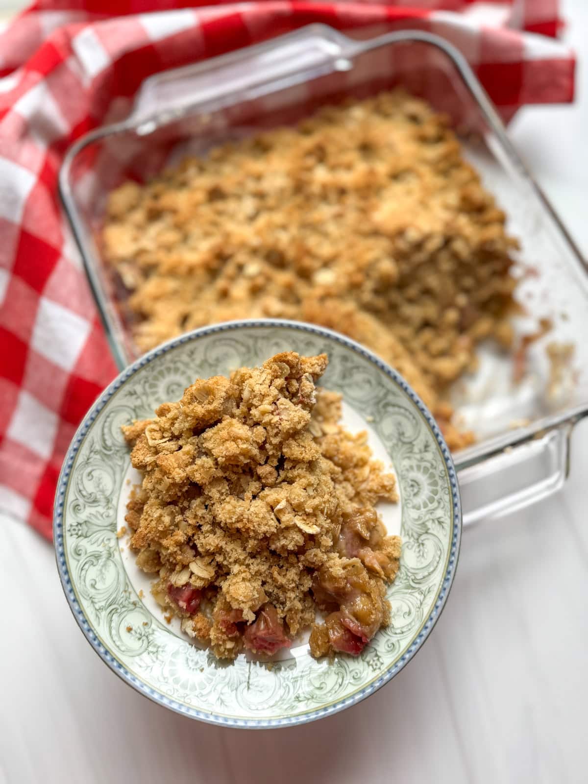 Serving of Classic Rhubarb Crisp on a plate above full pan.
