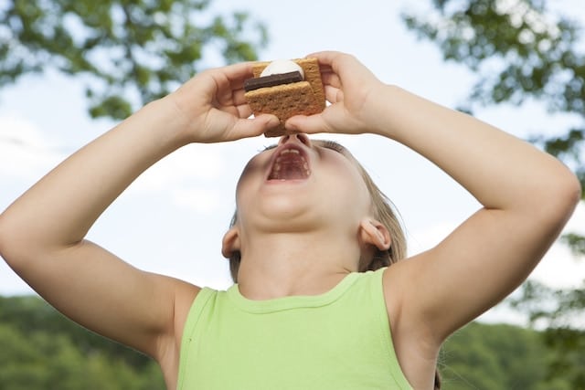 Child eating smore snack on camping trip