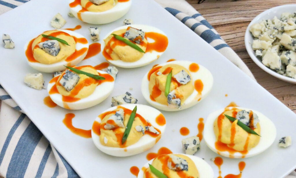 Buffalo Deviled Eggs on plate with blue cheese and buffalo sauce