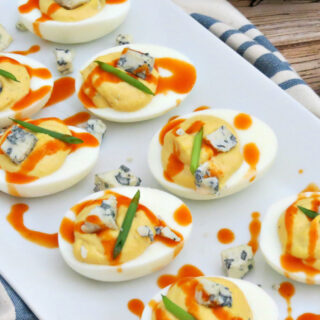 Buffalo Deviled Eggs on plate with blue cheese and buffalo sauce