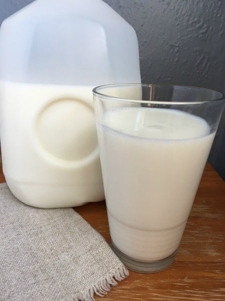 gallon of frozen milk defrosted with milk in a glass