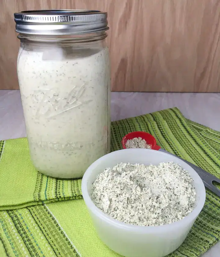 Homemade ranch dressing seasoning mix in a bowl with mason jar of ranch dressing in backround.