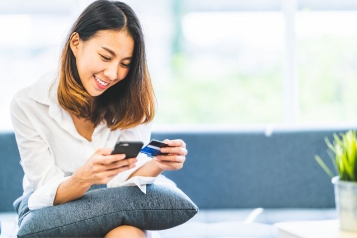Online Shopping - Woman on cellphone with credit card in hand.
