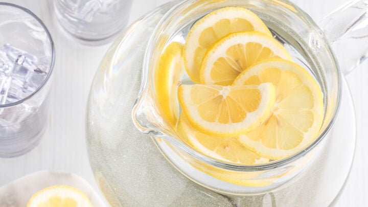 A top down view of a pitcher of lemon water with lemon slices ready for drinking.