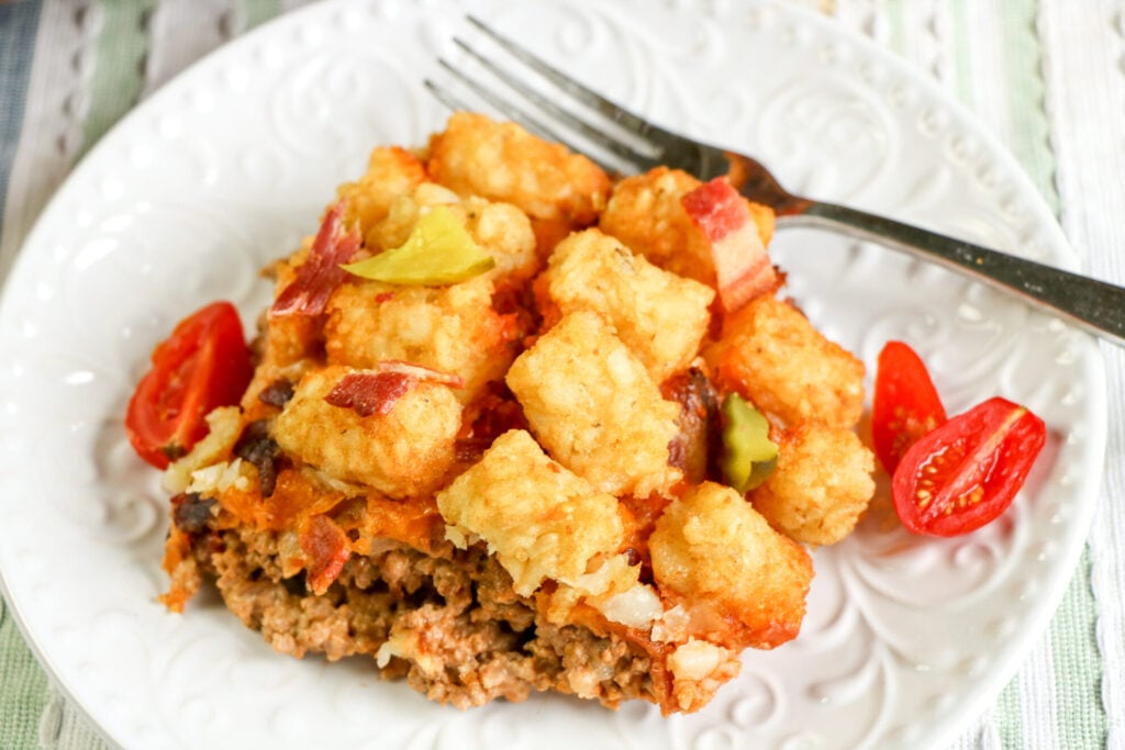 Bacon Cheeseburger Tater Tot Casserole on plate with fork and tomatoes on side