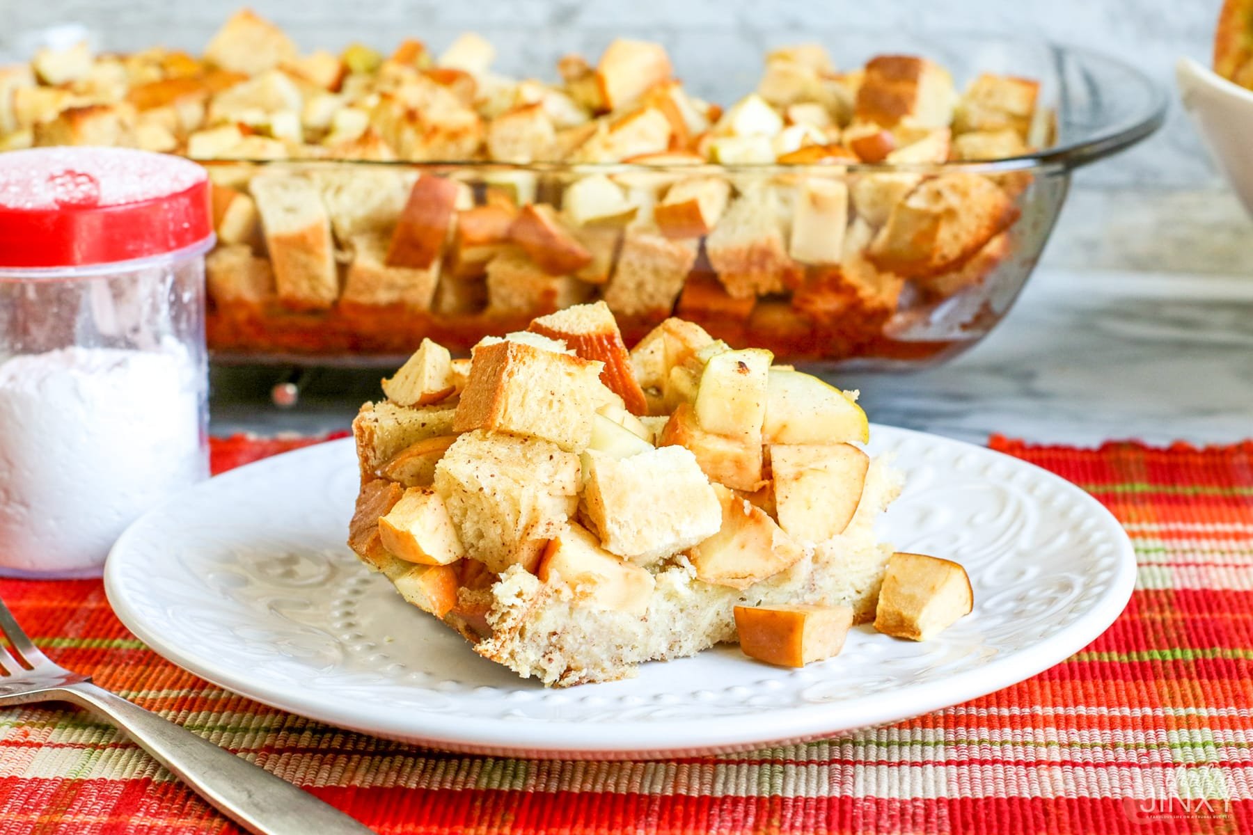 Apple Challah French Toast Casserole Served on a white plate with a fork.