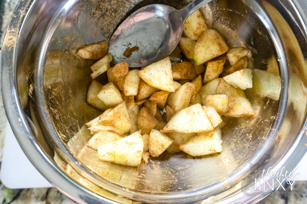 chopped apples in bowl with cinnamon, cardamom, and nutmeg.