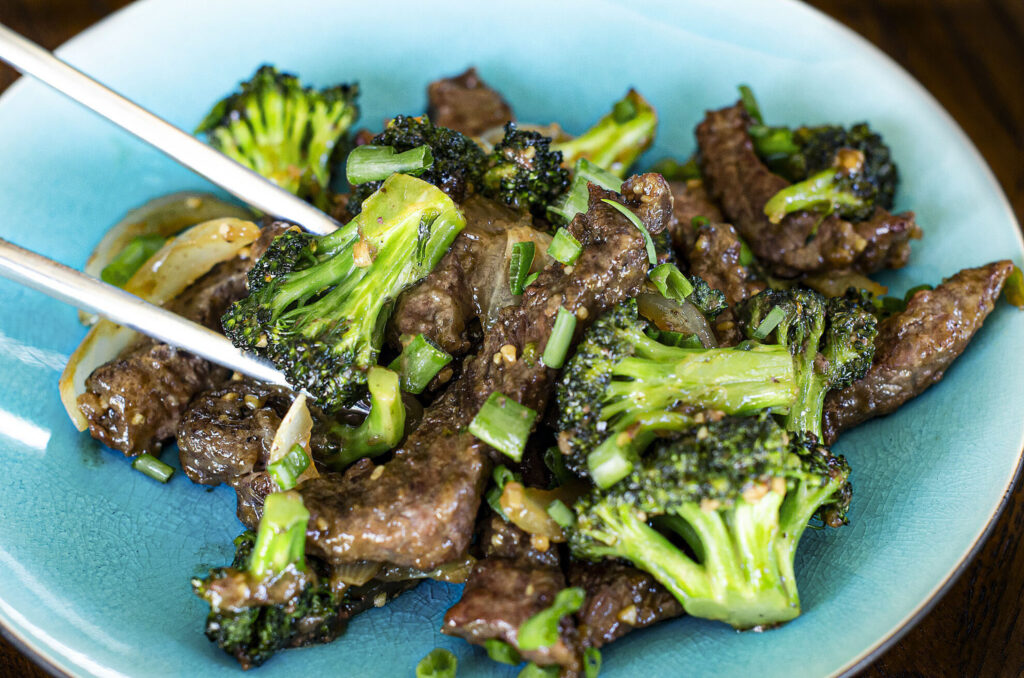 plate of beef and broccoli with chopsticks 