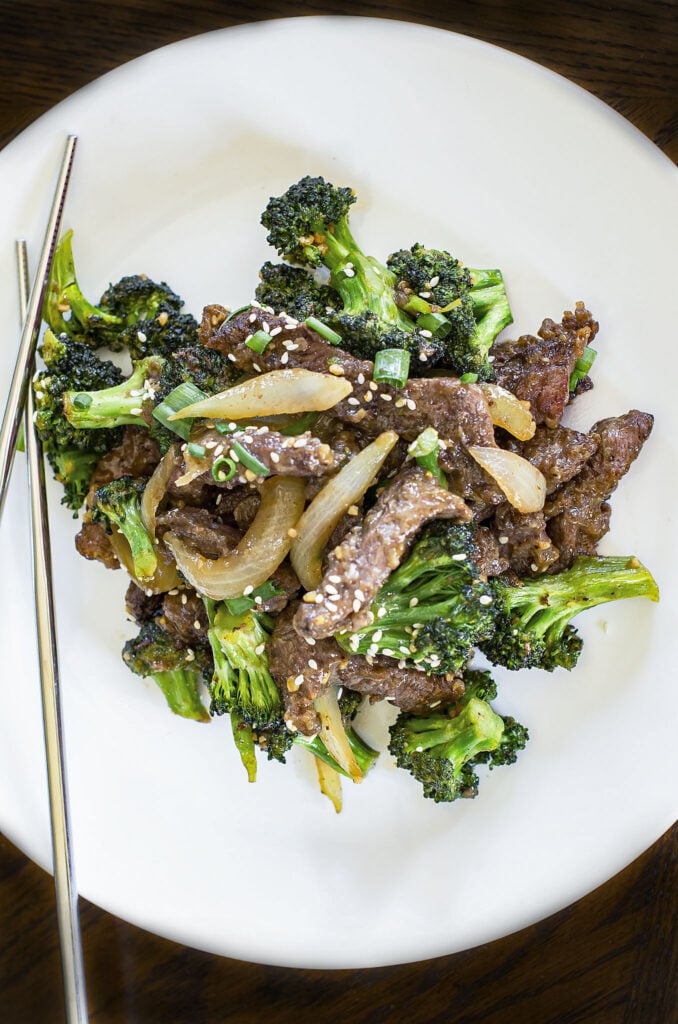 low carb beef and broccoli on white plate with chopsticks 