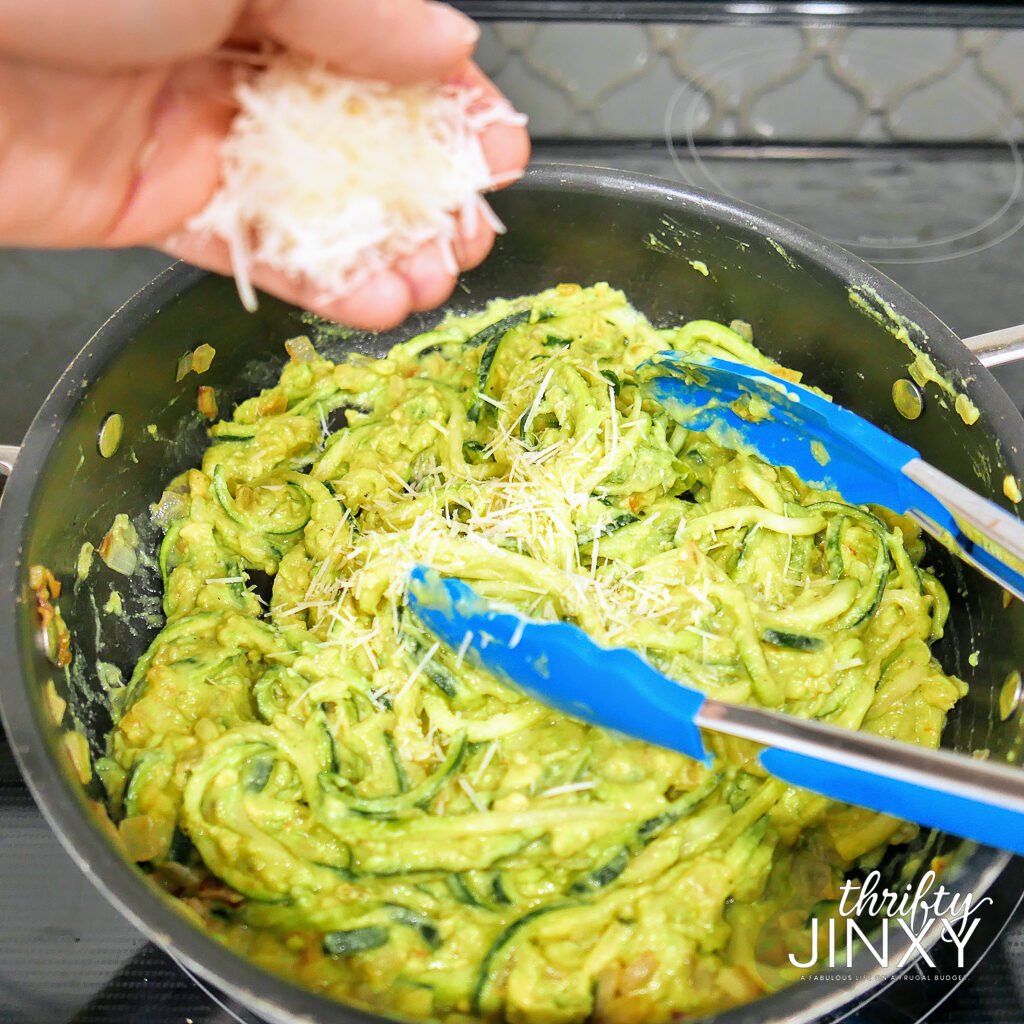 adding parmesan cheese to avocado zoodles