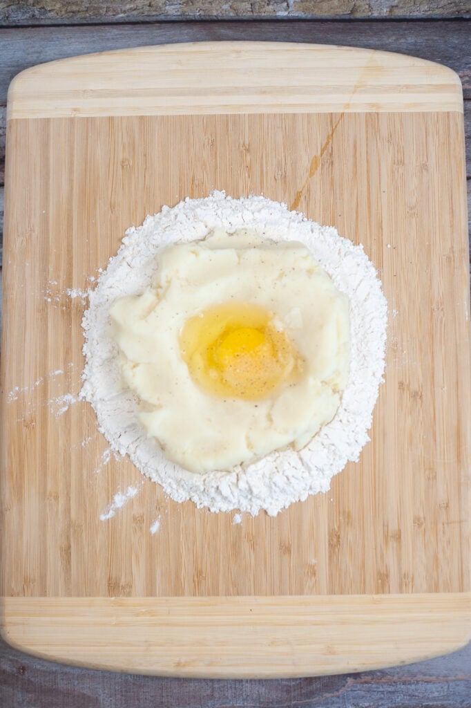 adding an egg into the middle of the flour mixture 