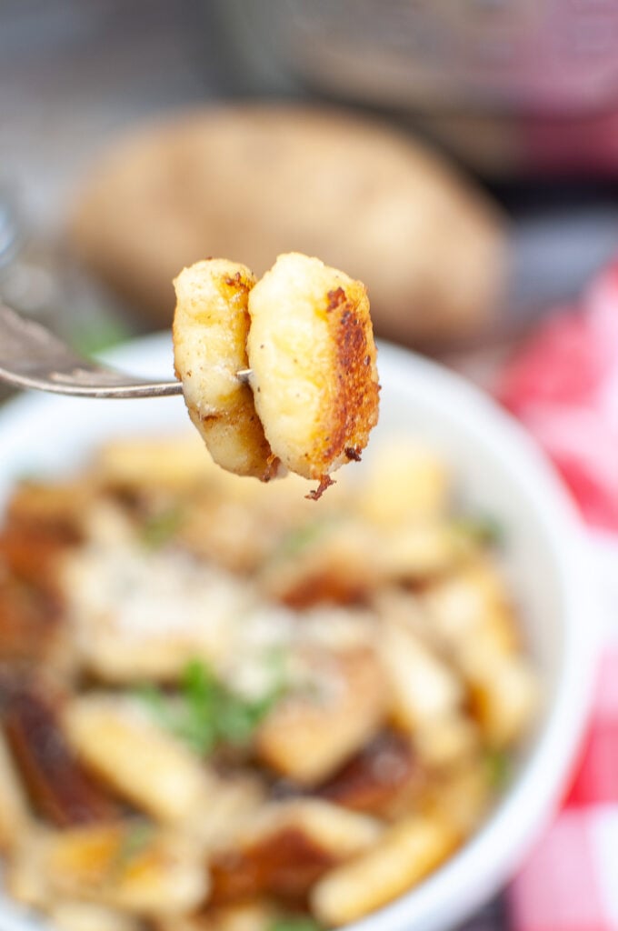 close up of a fork holding a piece of cooked gnocchi 