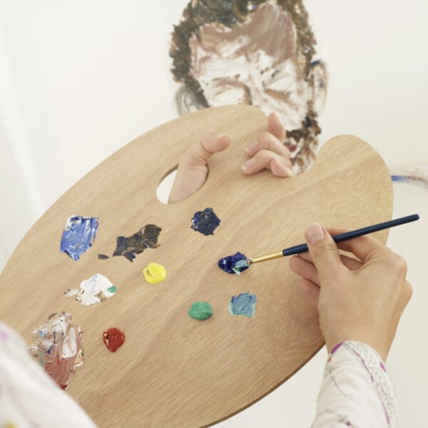 woman's hand holding palette and paintbrush