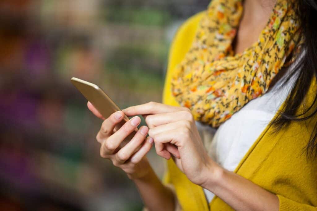 woman using phone in grocery store
