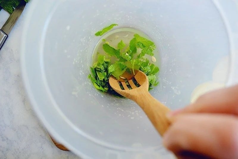 Mixing fresh mint and lemon juice with wooden spoon