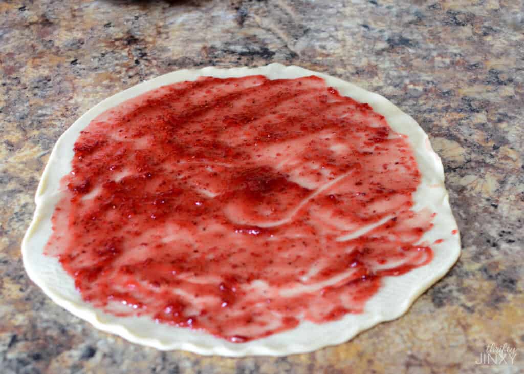 Spreading raspberry jam on pie crust to make Raspberry Pie Pops