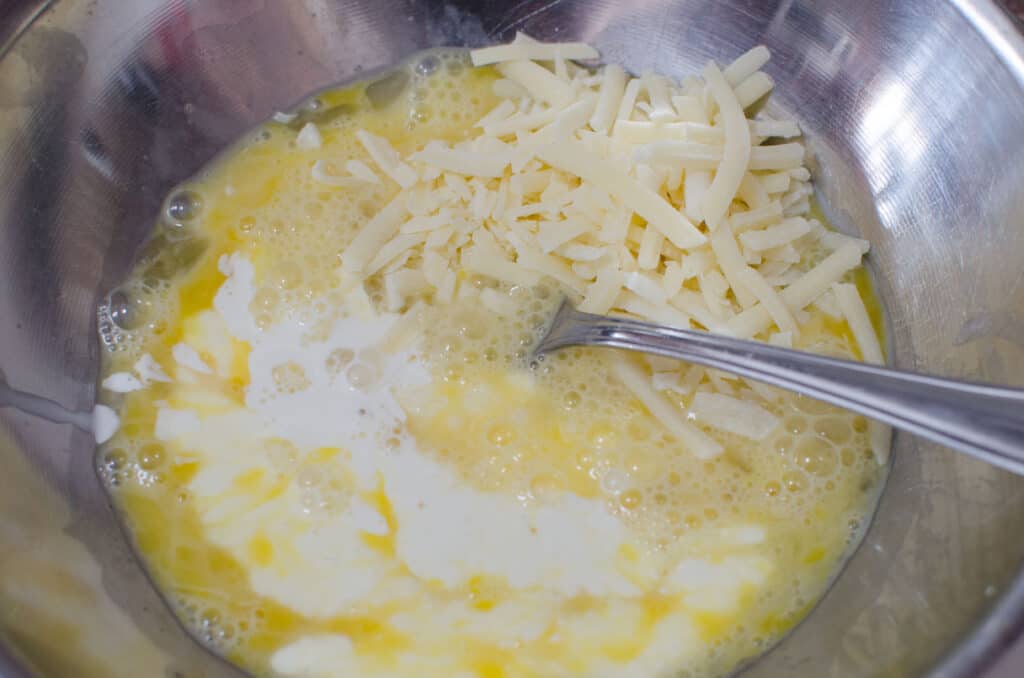 eggs milk cream and parmesan being whisked with cheese