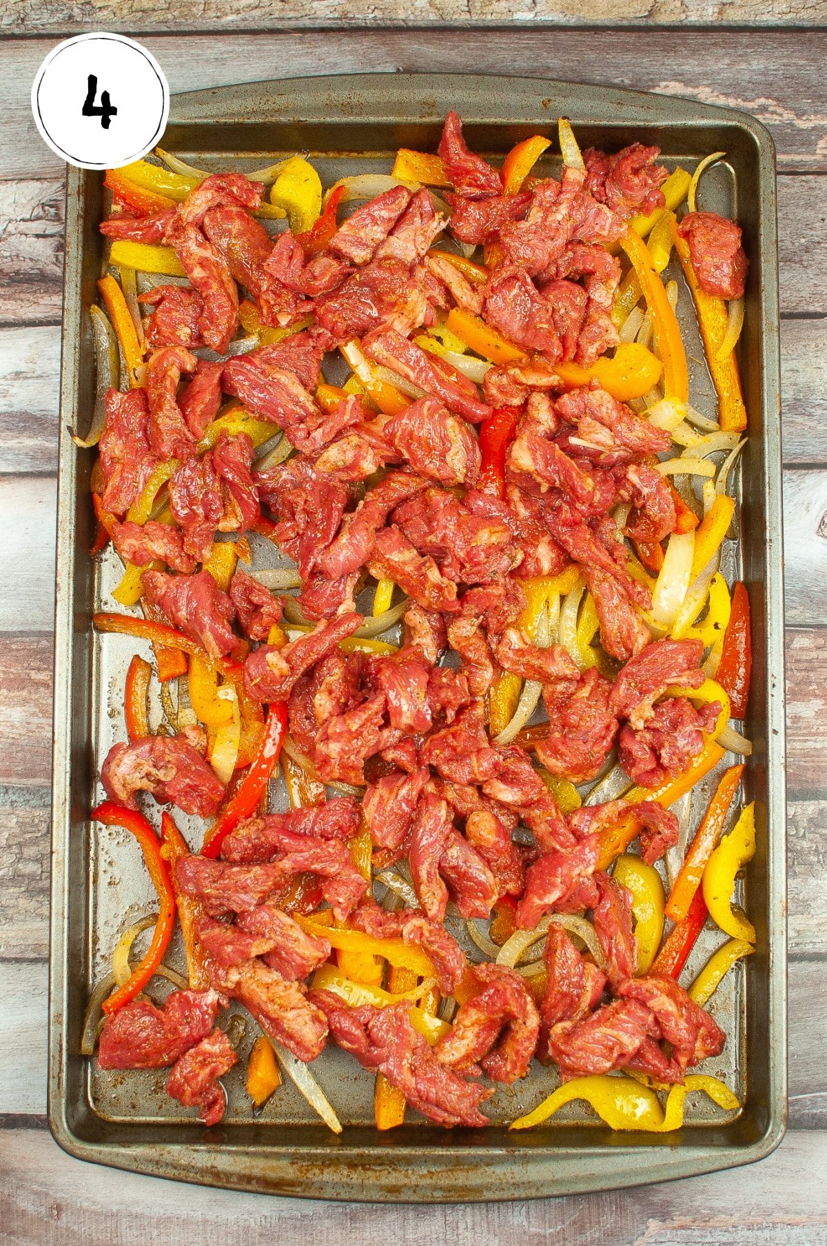 Steak, peppers and onions on roasting pan.