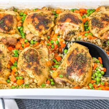 Chicken and Brown Rice Casserole in white baking dish with serving spoon.