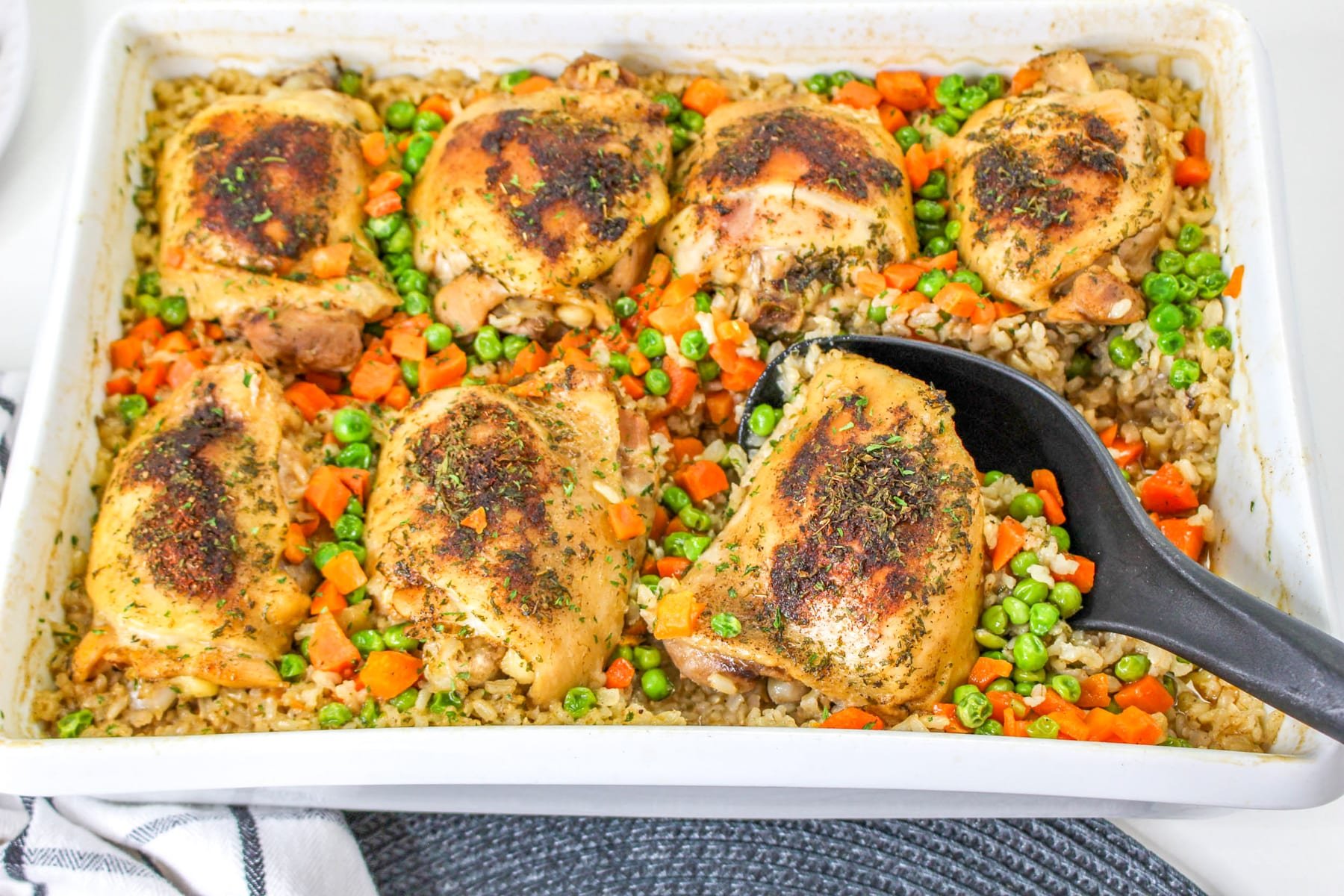 Chicken and Brown Rice Casserole in baking dish with serving spoon.