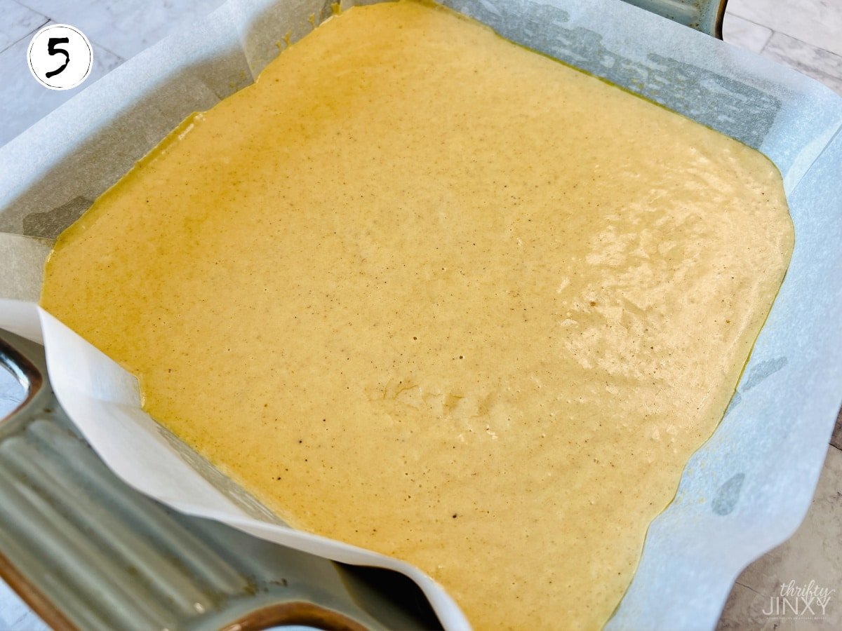 pouring pumpkin fudge mixture into parchment paper lined baking pan.