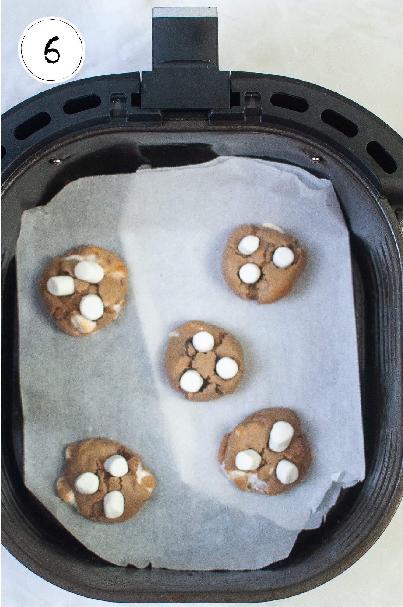 Adding marshmallows to hot chocolate cookies in air fryer.