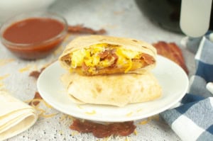 2 Copycat Taco Bell Breakfast Crunchwraps on a white plate, one showing the inside