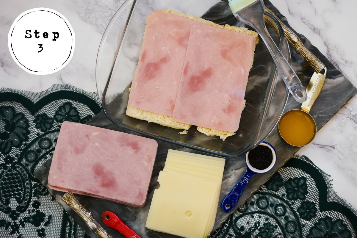 adding ham to bread for Ham and Swiss Sliders recipe.