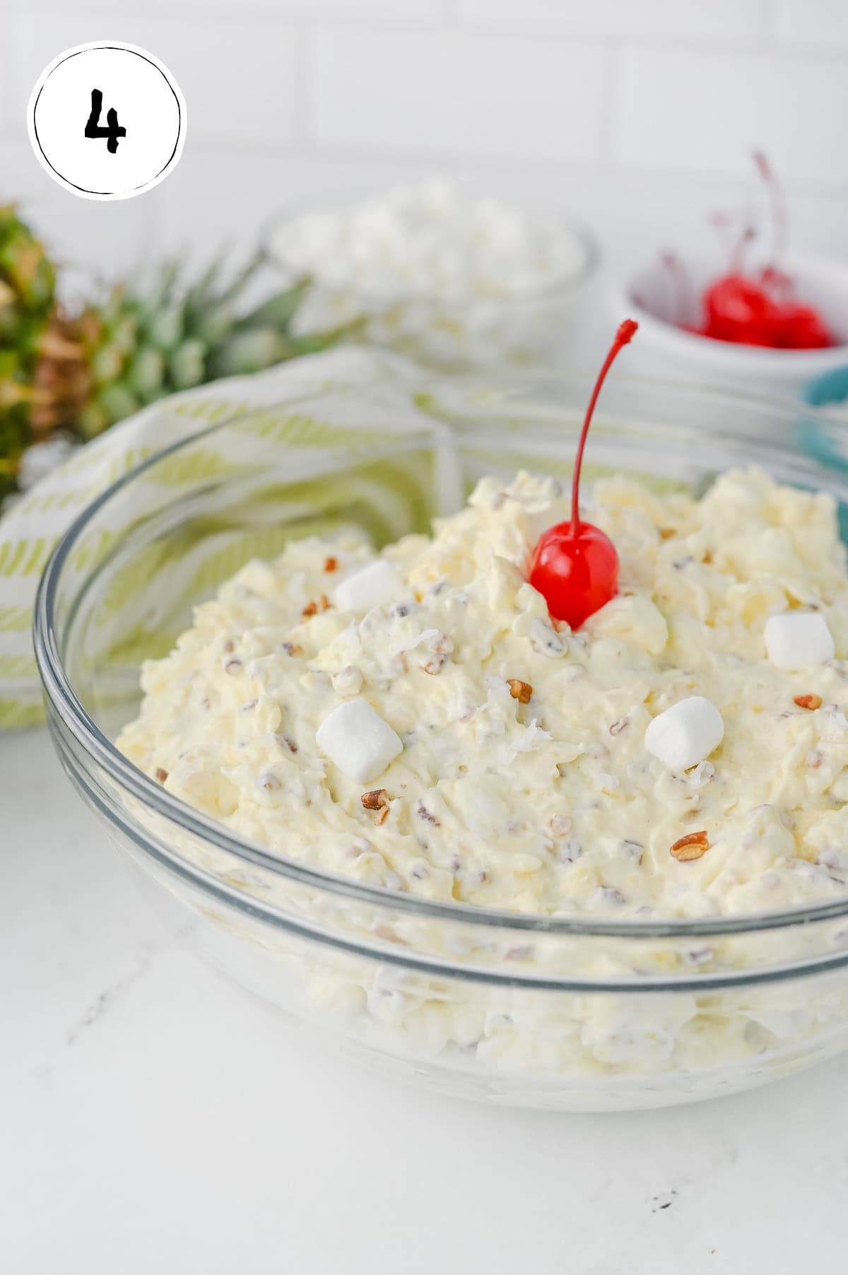 Adding Maraschino Cherry to Pina Colada Marshmallow Salad.