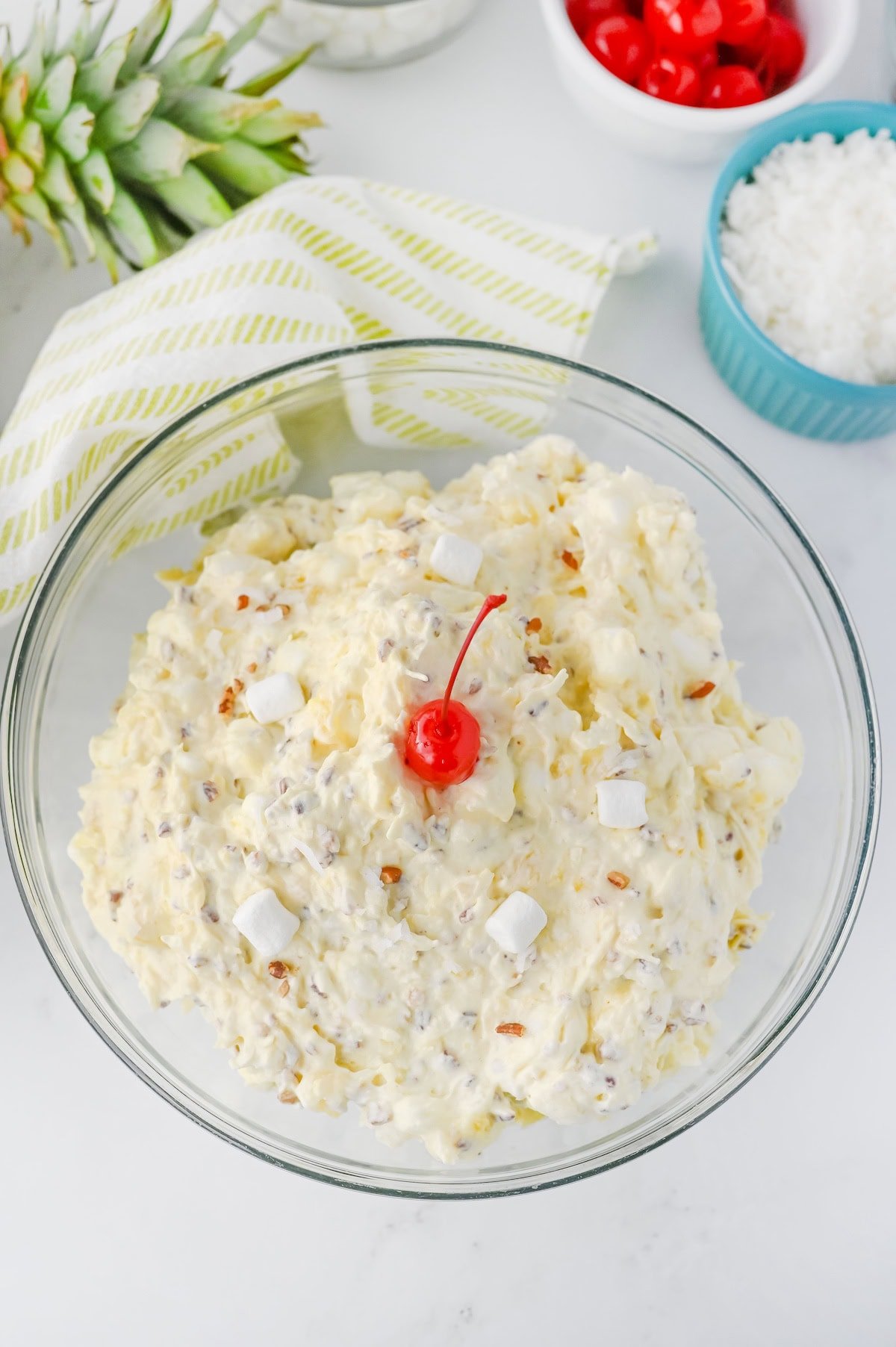 Piña Colada Marshmallow Fluff Salad in bowl topped with maraschino cherry.