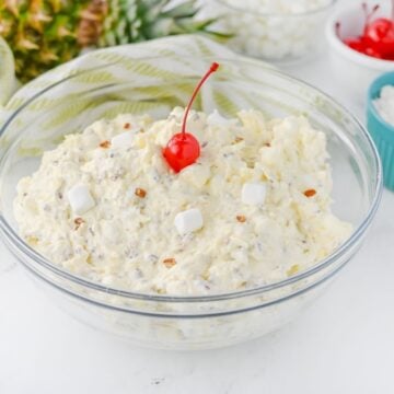 Piña Colada Marshmallow Salad in glass bowl topped with a maraschino cherry.