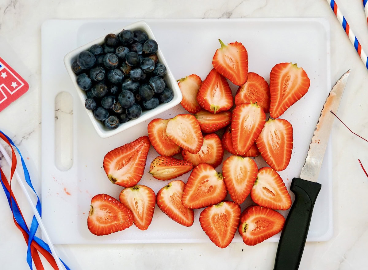 Prepping strawberries on cutting board for flag fruit tray.