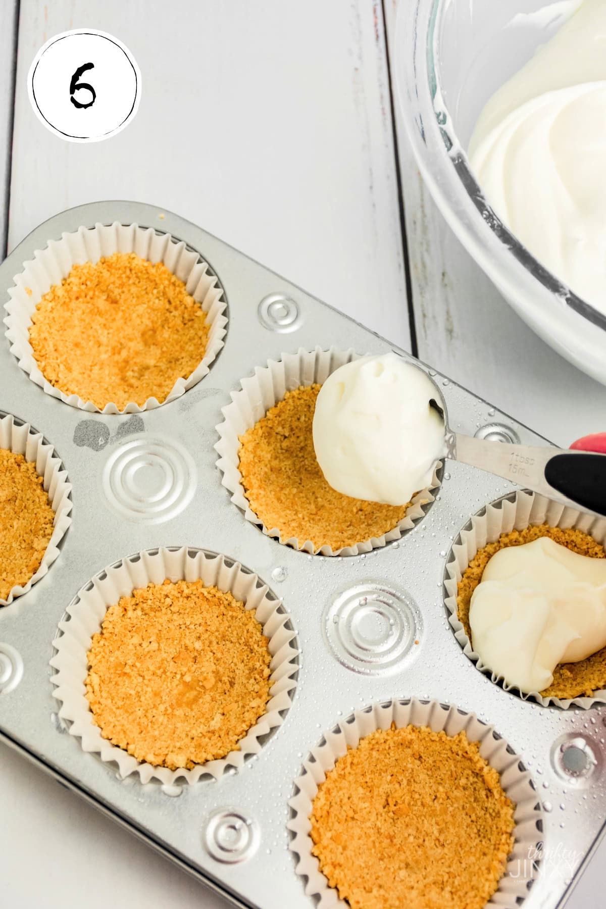 Filling graham cracker crusts with filling for Mini No Bake Cheesecakes.