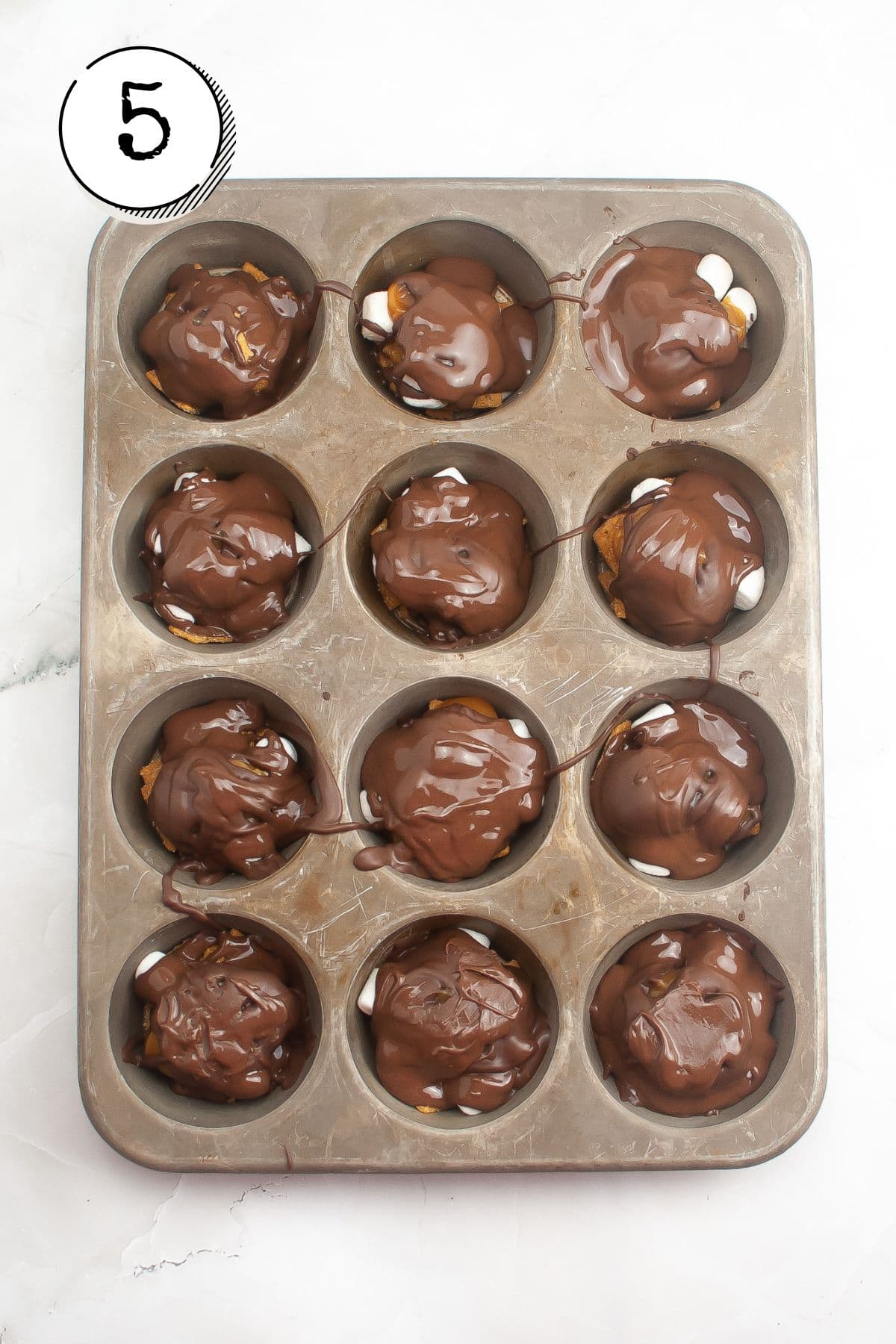 Pouring melted chocolate over each cluster, covering most of the top.