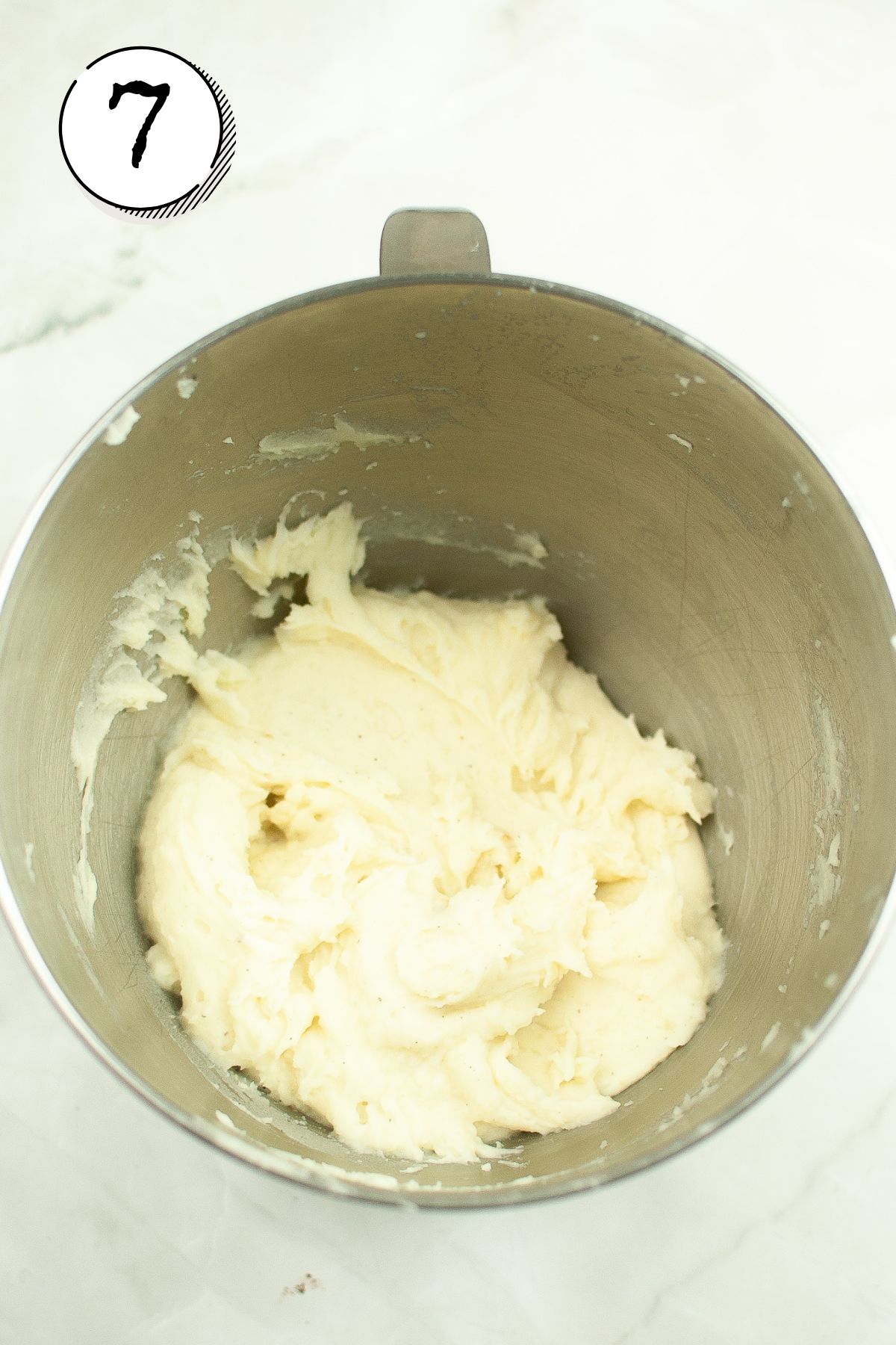 Adding the scooped potato to a mixing bowl and adding the butter, salt, and pepper, and half and half.
