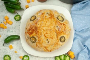 Jalapeno Cheddar No Knead Bread featured image in a white plate surrounded by jalapenos