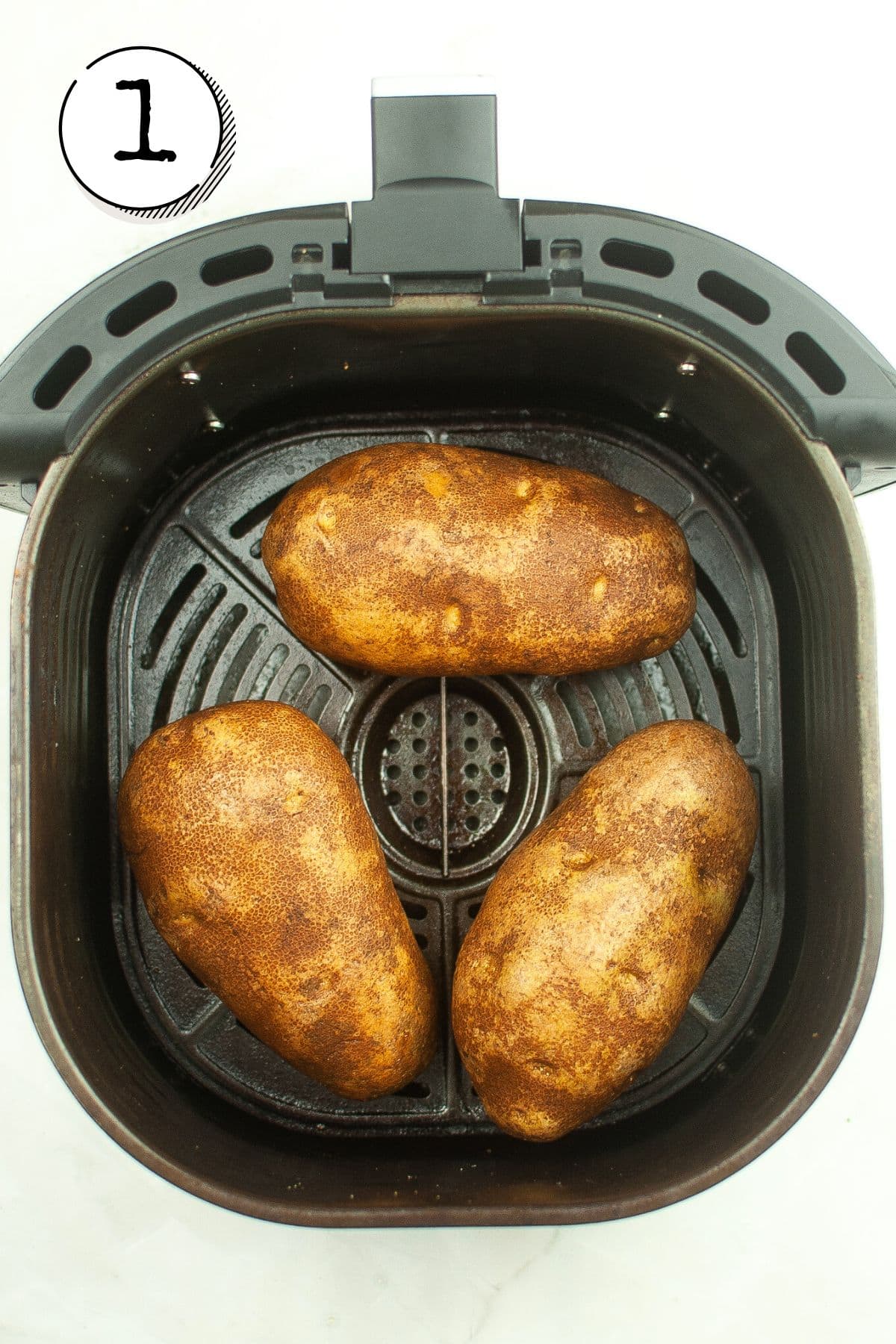 Placing potatoes in a preheated air fryer basket.