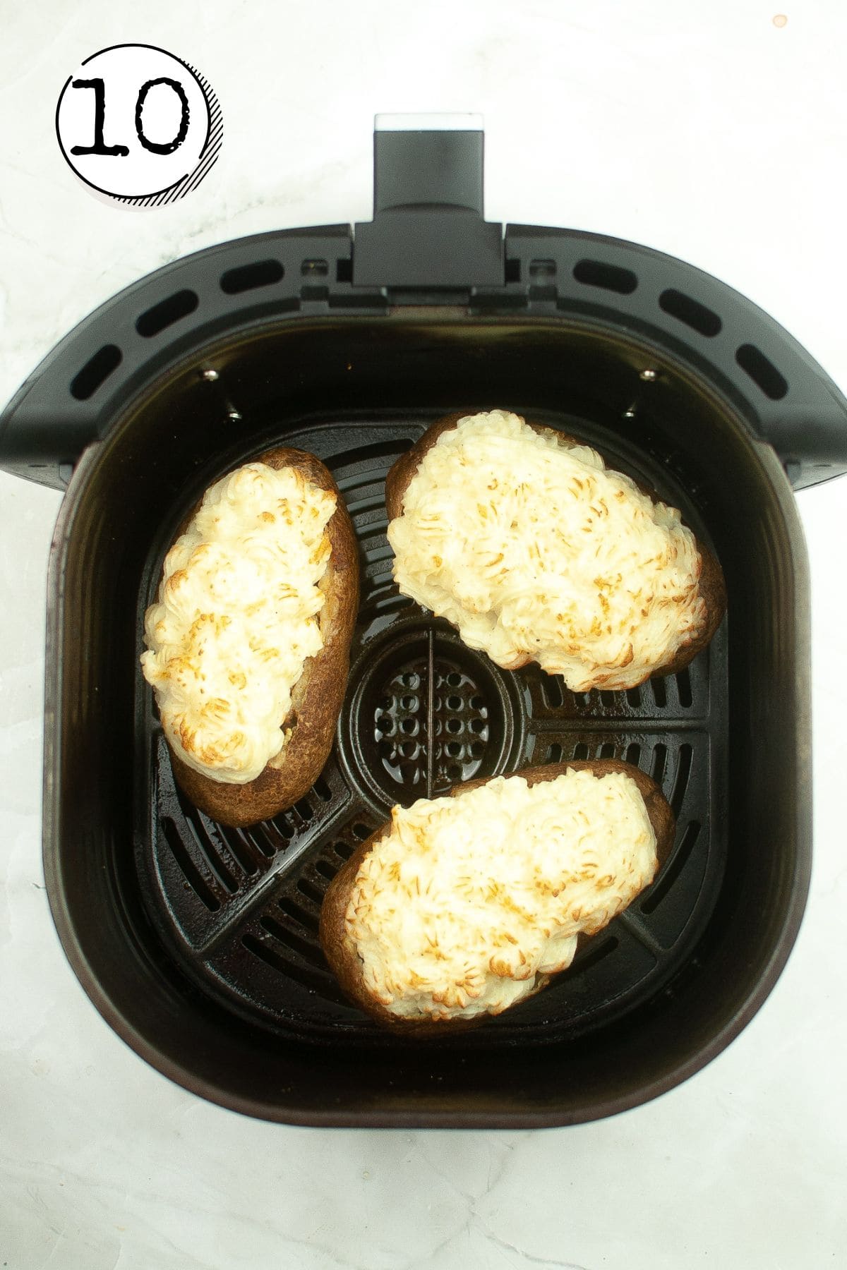 Returning the potatoes to the air fryer.