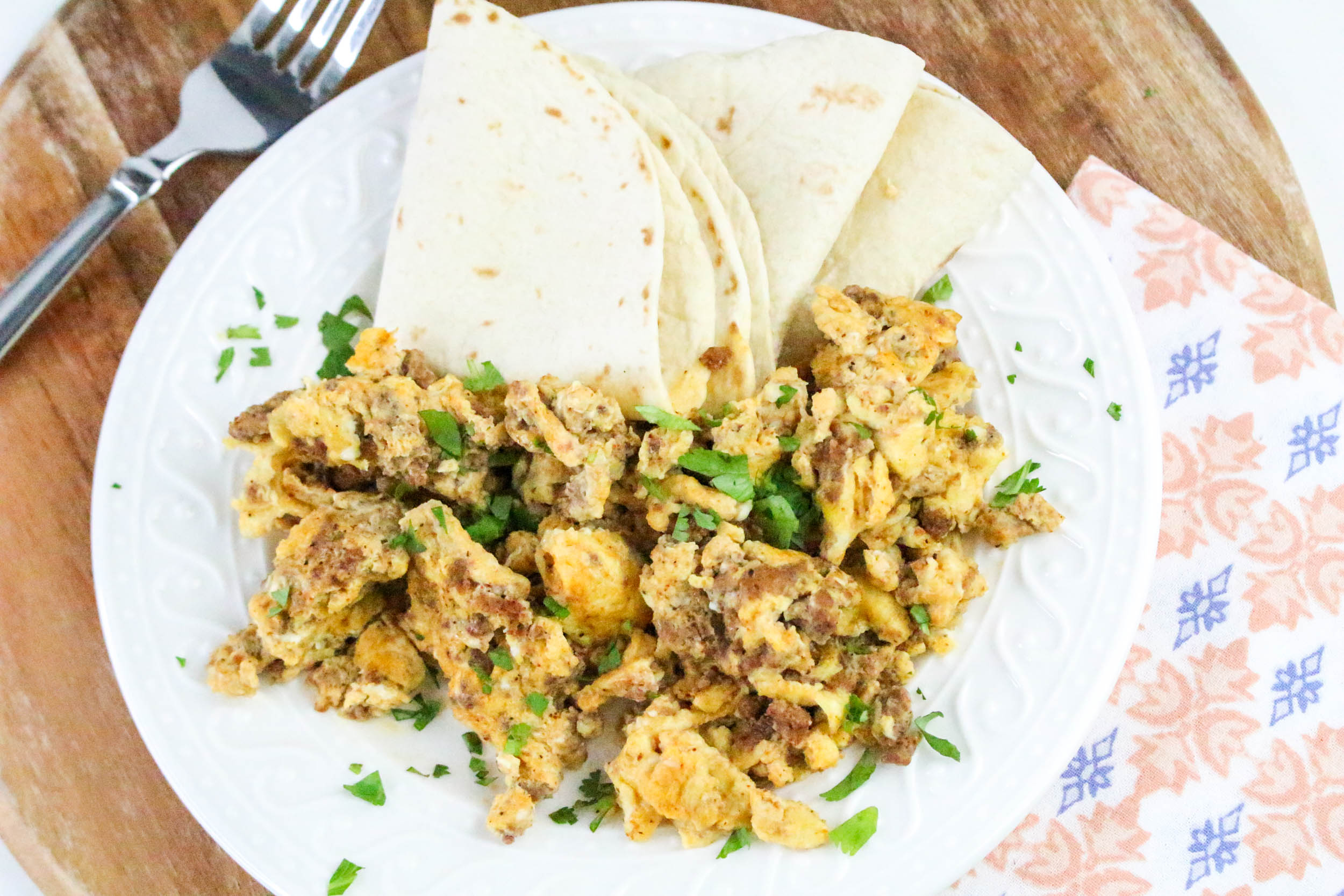 Chorizo and Eggs with tortilla on the side in white plate