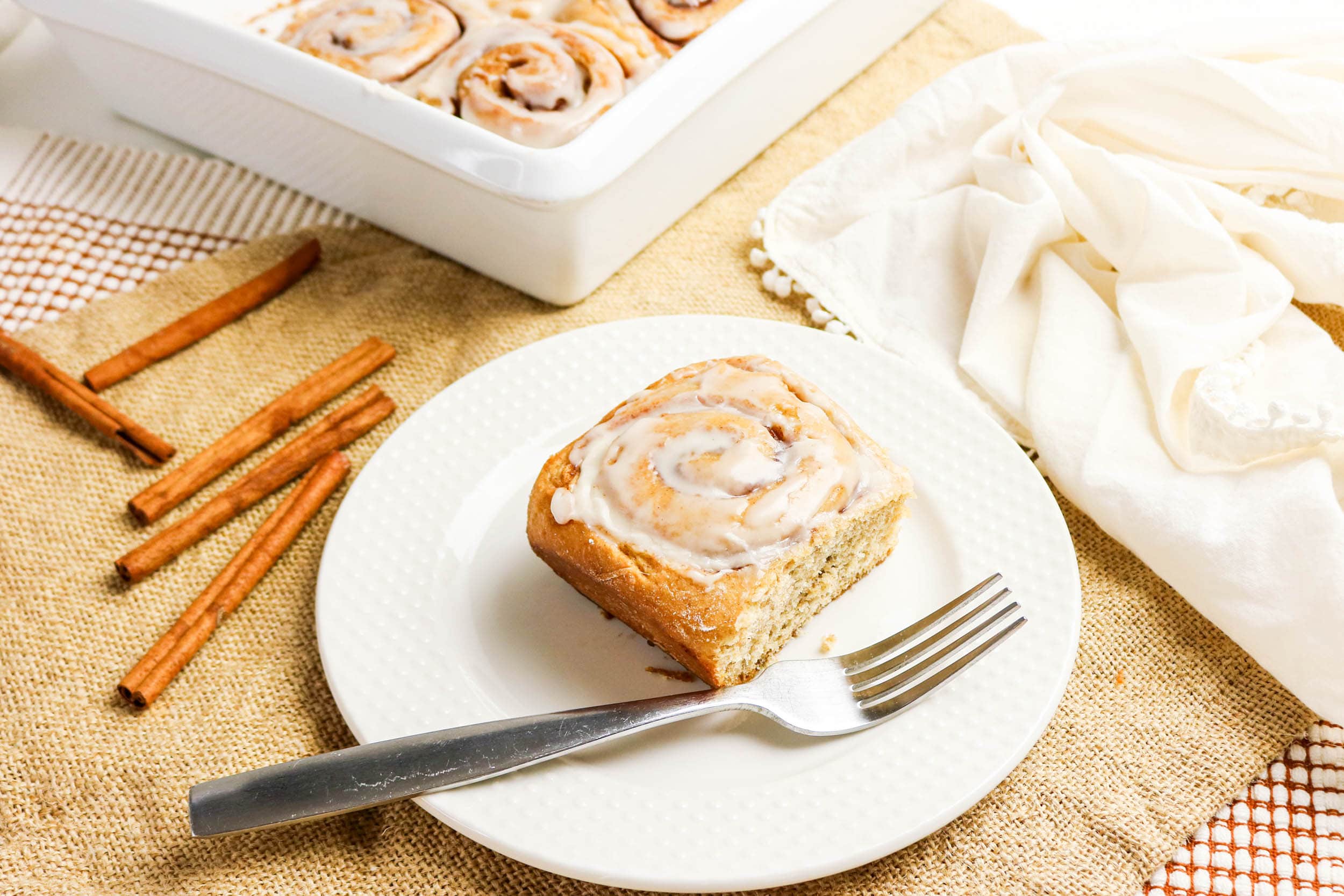 Whole Wheat Cinnamon Rolls a slice with fork and a tray with cinnamon sticks